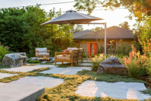 Lawn area with plants, trees, table, chairs, sofa around fire pit